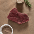 Raw bison filet steak with herbs and spices on a brown surface