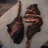 Grilled Bison tomahawk steak on a wooden cutting board with a rustic background