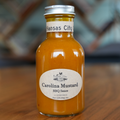 Bottle of Carolina Mustard BBQ Sauce on a wooden surface with a blurred background