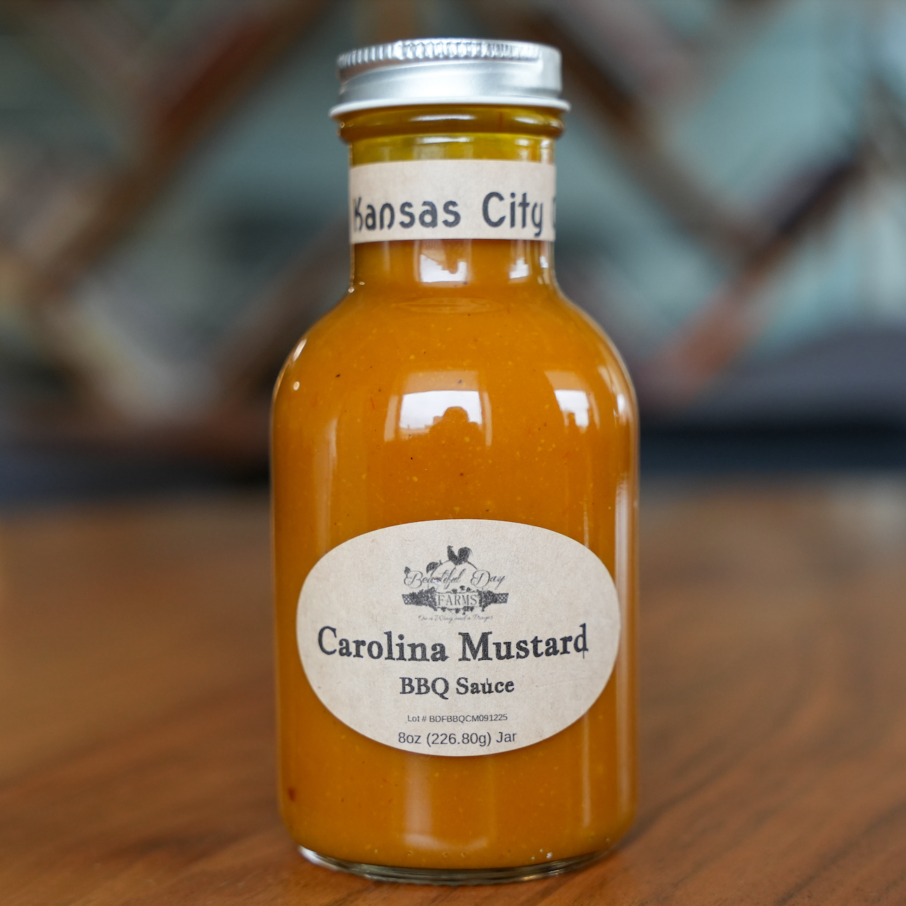 Bottle of Carolina Mustard BBQ Sauce on a wooden surface with a blurred background