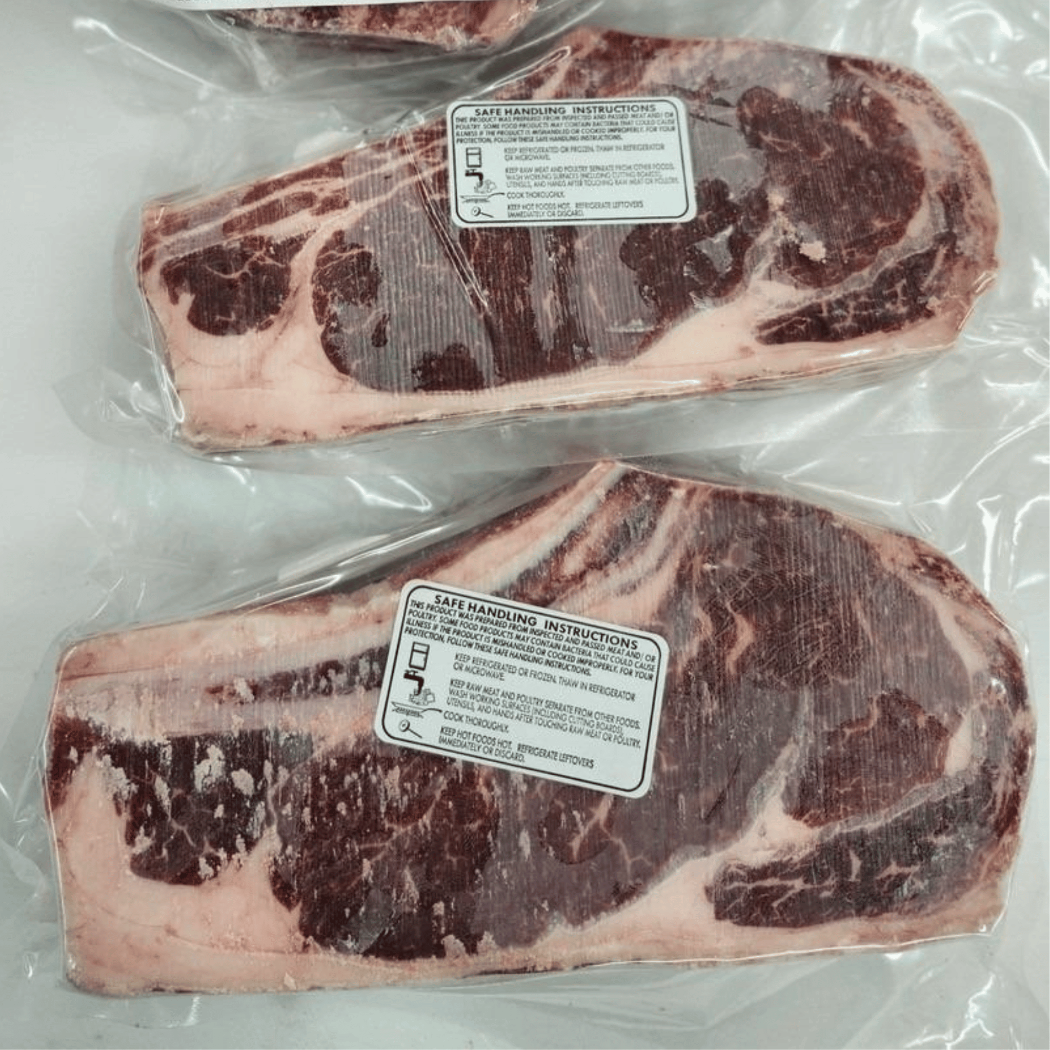 Two packages of raw beef with handling instructions labels on a white background
