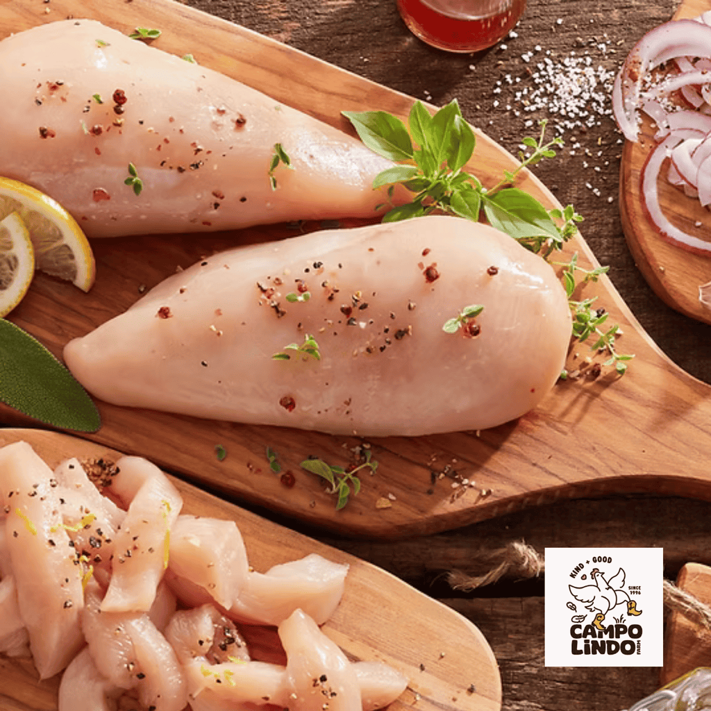 Raw chicken breasts on a wooden board with herbs and spices, Campo Lindo logo visible.